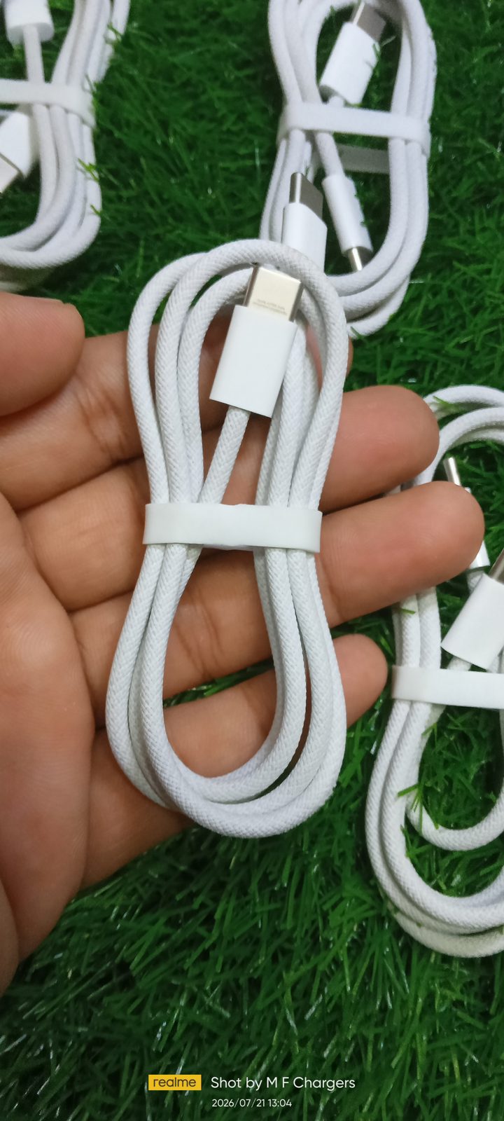 Coiled Original Apple Braided Type-C to Type-C Cable with paper band being held up to show detailed cable texture by M F Chargers.