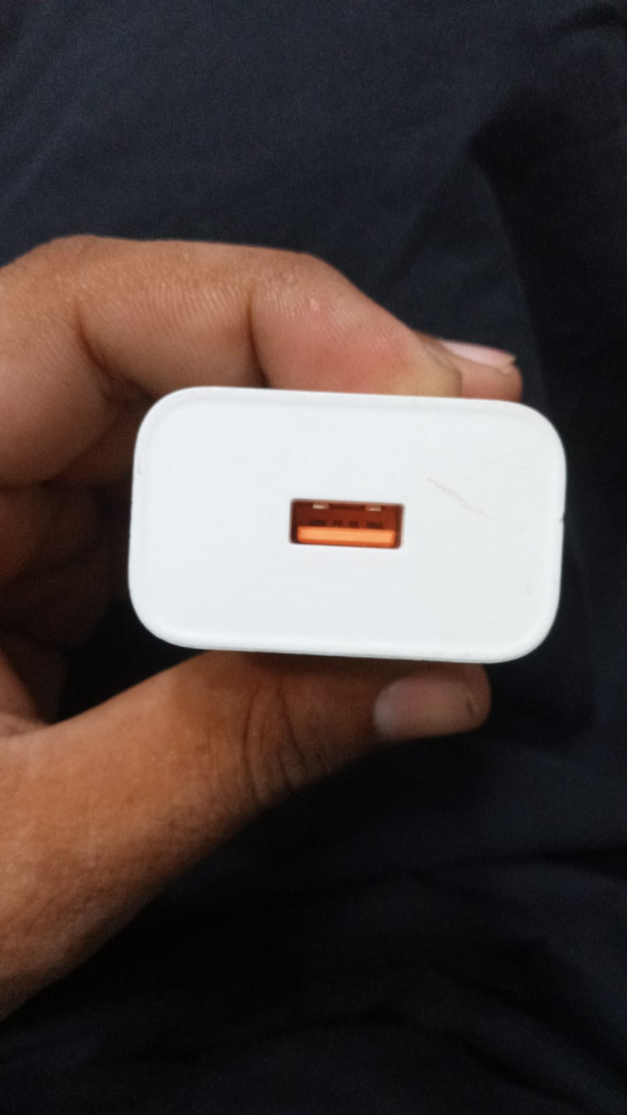Close up view of original Tecno 33W fast charger adapter showing its genuine orange USB port.