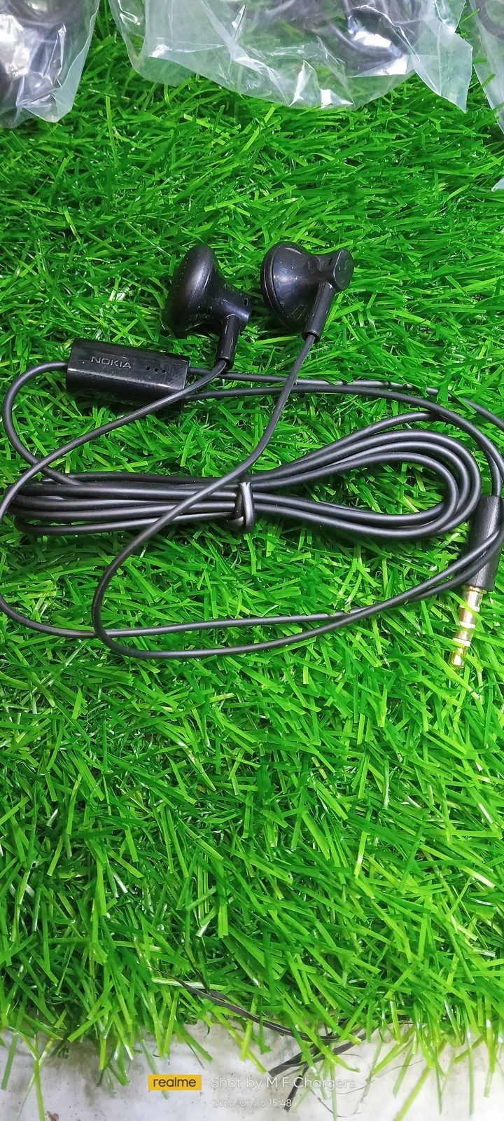Genuine Nokia WH-108 wired earphone black cable spread on green grass by M F Chargers