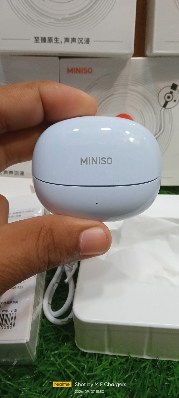 Light blue Miniso wireless earbuds charging case in hand - M F Chargers